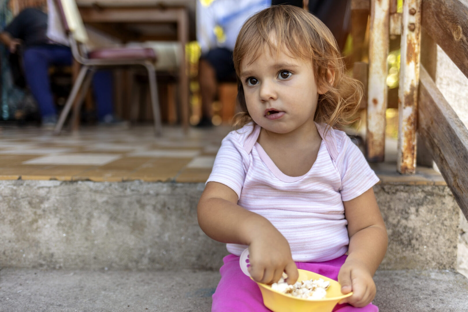 Toddler sitting with bowl of popcorn.